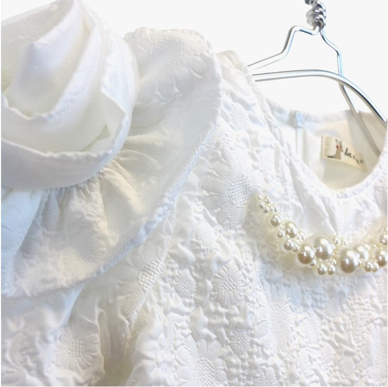Close-up detail of pearl collar neckline and white rosette sleeve embellishment on girls' brocade dress