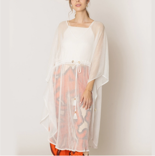 Woman wearing a sheer white cover-up with a patterned bottom on a plain background