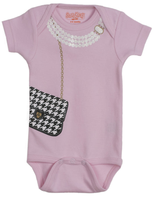 Flat lay of pink houndstooth purse onesie with pearl necklace