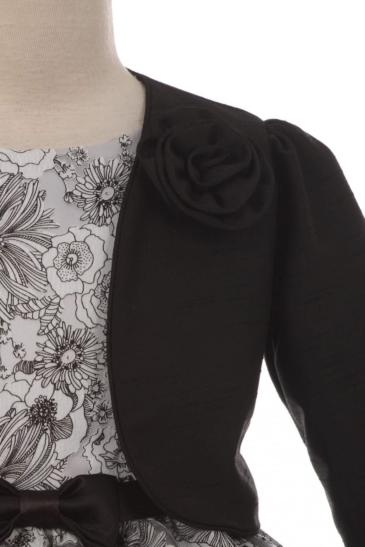 Close-up detail of black satin bolero jacket with long sleeves over silver floral embroidered dress