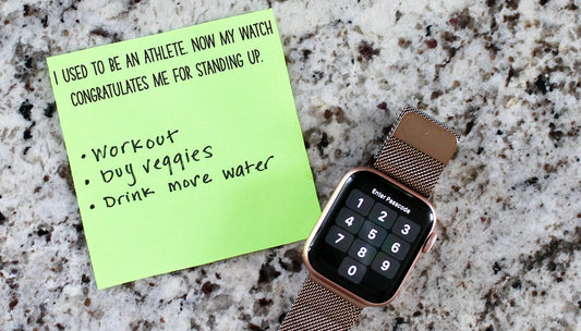 Smartwatch with a rose gold band on a granite surface next to a green sticky note with text.