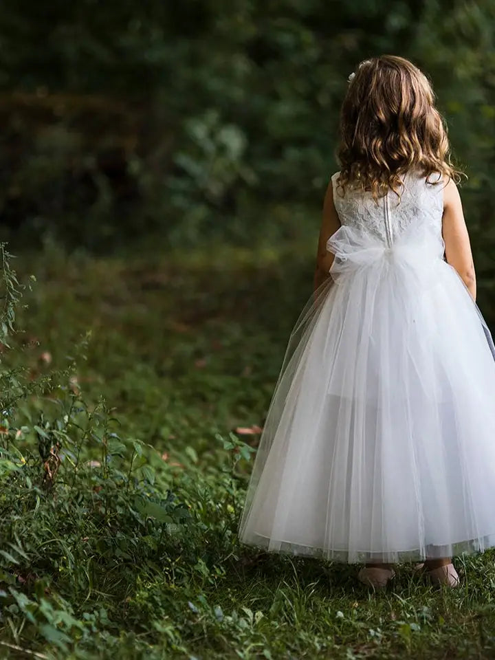 Back view of girls' white lace dress showing statement bow sash and layered tulle skirt