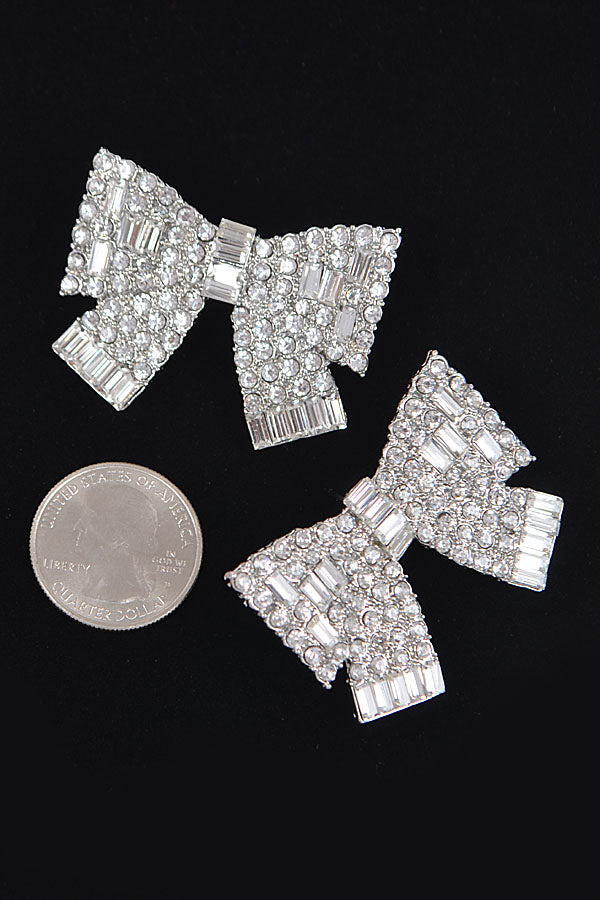 Silver rhinestone bow stud earrings with US quarter coin showing size comparison on black background