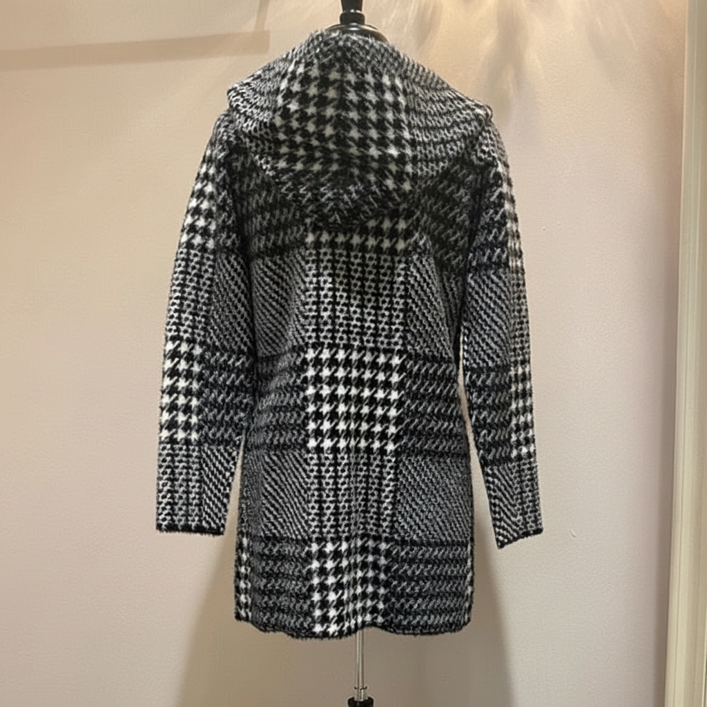 Black and white houndstooth hooded coat showing back view with oversized hood and geometric pattern detail on dress form