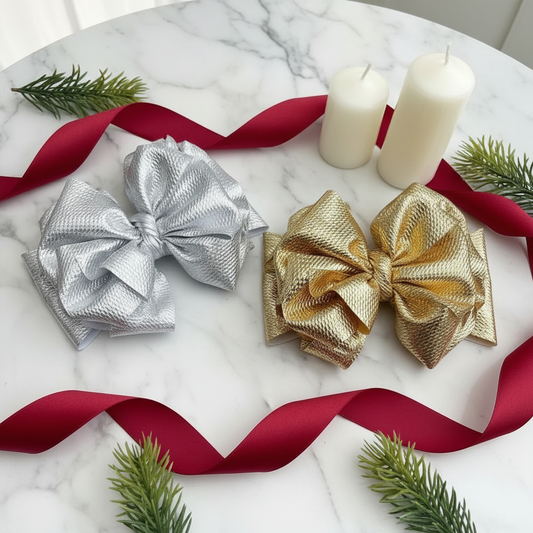 Gold and silver metallic bow headbands styled with holiday decor, red ribbon, and candles