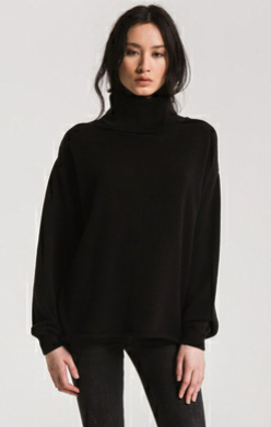 Woman wearing black Z Supply drop shoulder turtleneck sweater styled for casual-chic layering