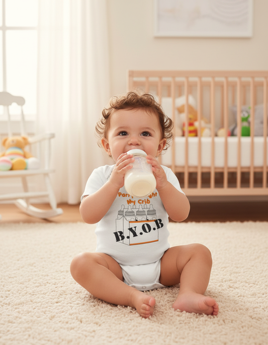 Baby wearing white BYOB onesie with baby bottle graphics, sitting with bottle
