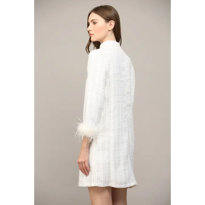 Side profile of white metallic lurex mini dress with dramatic feather sleeve cuffs and mock neckline