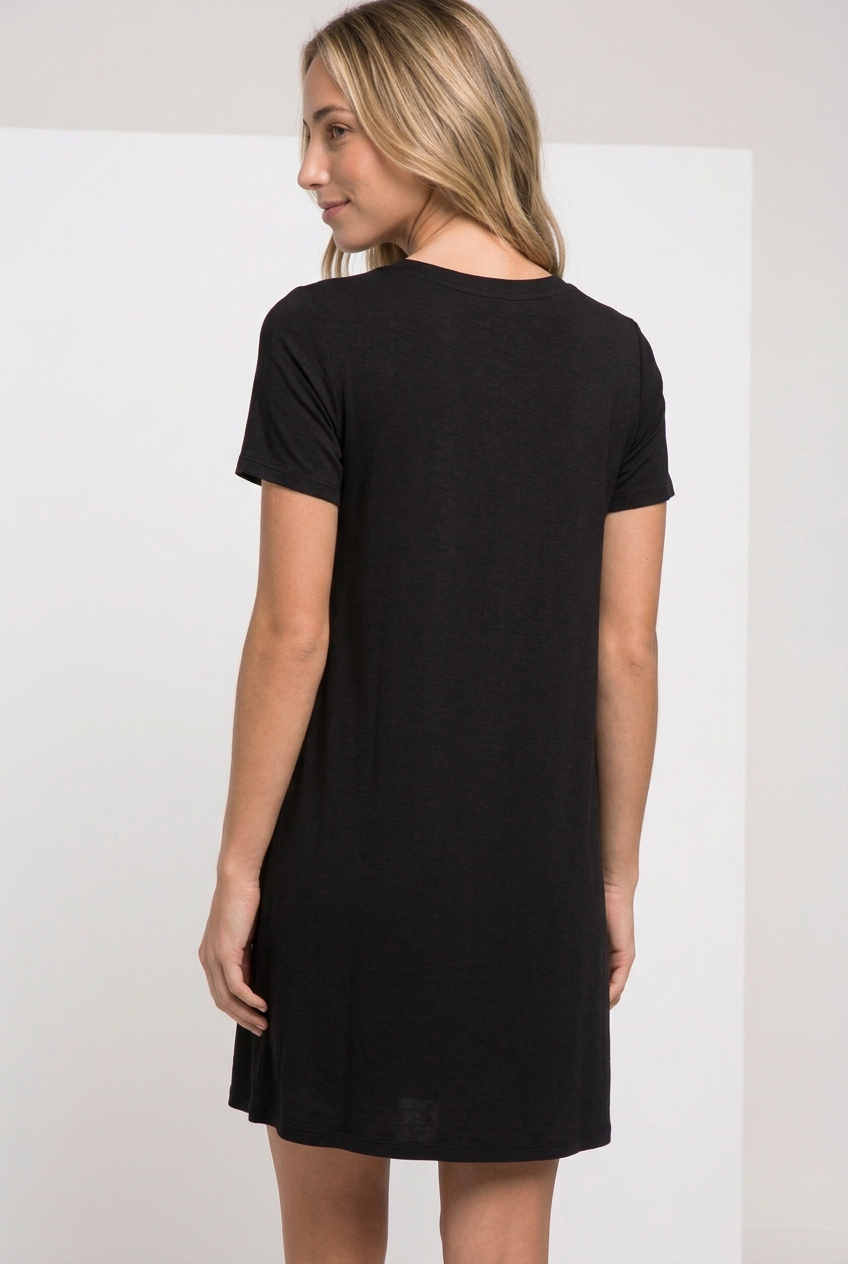 Back view of black short-sleeve T-shirt swing dress with a plain high round neckline, shown on a blonde model looking over her shoulder.
