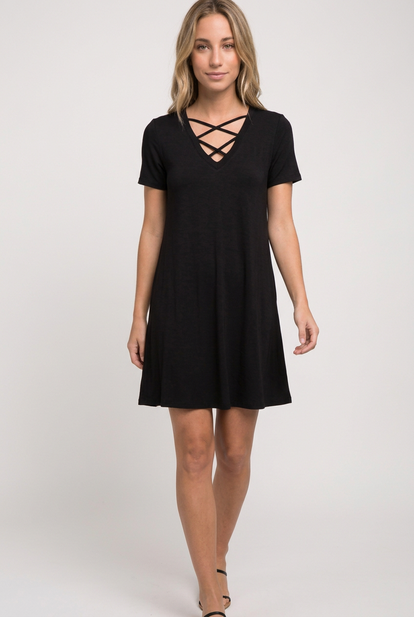 Black double-crisscross V-neck T-shirt swing dress with short sleeves, shown on a blonde model stepping forward for a casual weekend look.