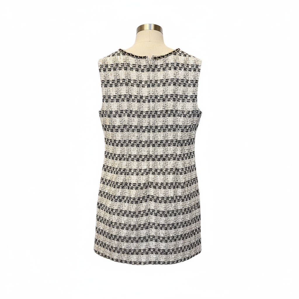 Back view of black and white tweed sleeveless dress with gold chain trim and zipper closure on white background