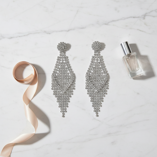 Luxury flat lay of 3.5-inch diamond accent chandelier earrings on white marble with elegant accessories