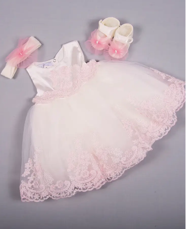 Baby pink and white lace christening dress set with glitter accents, matching pink tulle headband and satin booties on gray background
