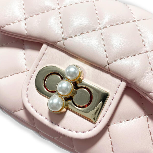 Close-up detail of pearl charm closure on quilted girls purse showing gold hardware