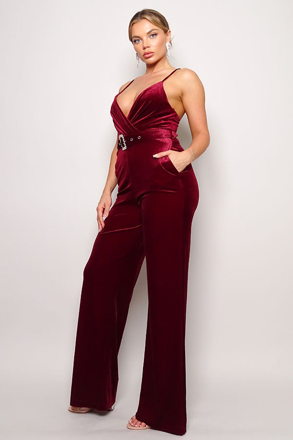 Side view of woman in red velvet wide-leg jumpsuit with sparkling rhinestone waist belt