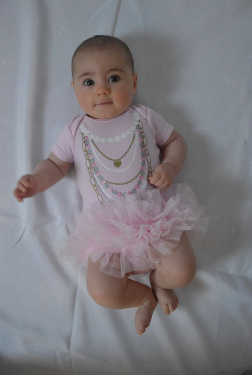 Close-up of pink baby onesie showing printed pearl and necklace details
