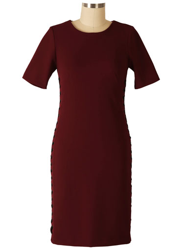 Wine-colored sheath dress with elbow-length sleeves and side lace-up detail, displayed on dress form against neutral background