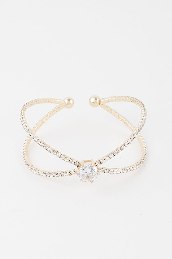 Cubic zirconia crossover cuff bracelet in gold finish with center stone accent against white background