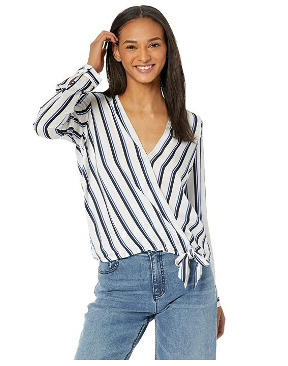 Woman wearing white and navy striped tie-front surplice blouse with V-neckline and blue jeans