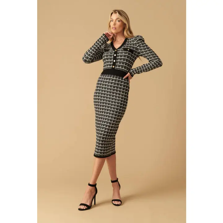Woman wearing black and white boucle knit midi dress with V-neckline, long puff sleeves and gold button details, front view"