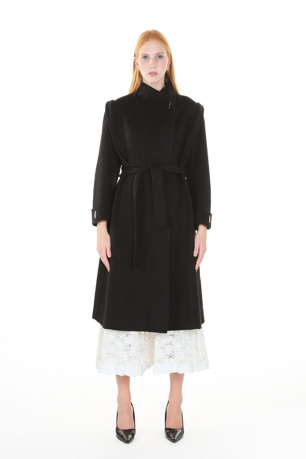 Woman wearing a black coat over a white dress on a white background