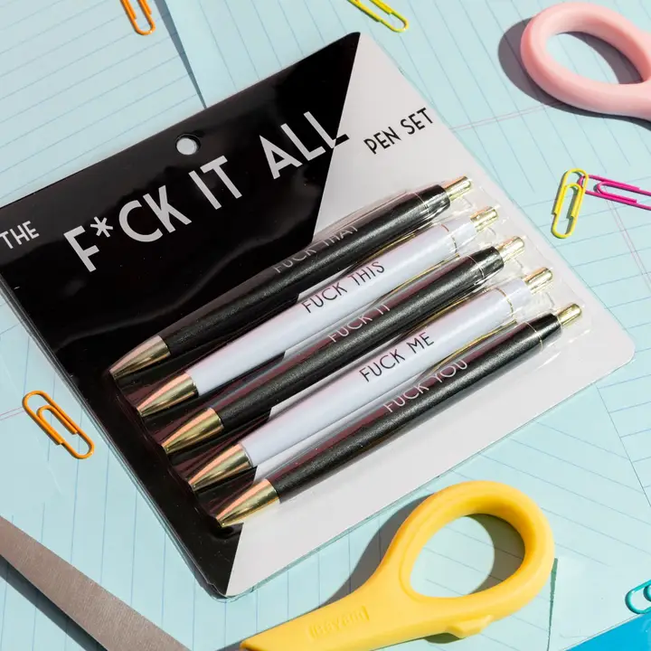This image features a pen set branded as "F*CK IT ALL," presented in a bold, black packaging. The set includes several pens, each with a distinct phrase printed on them, such as "F*CK THIS," "F*CK ME," and "F*CK IT ALL.