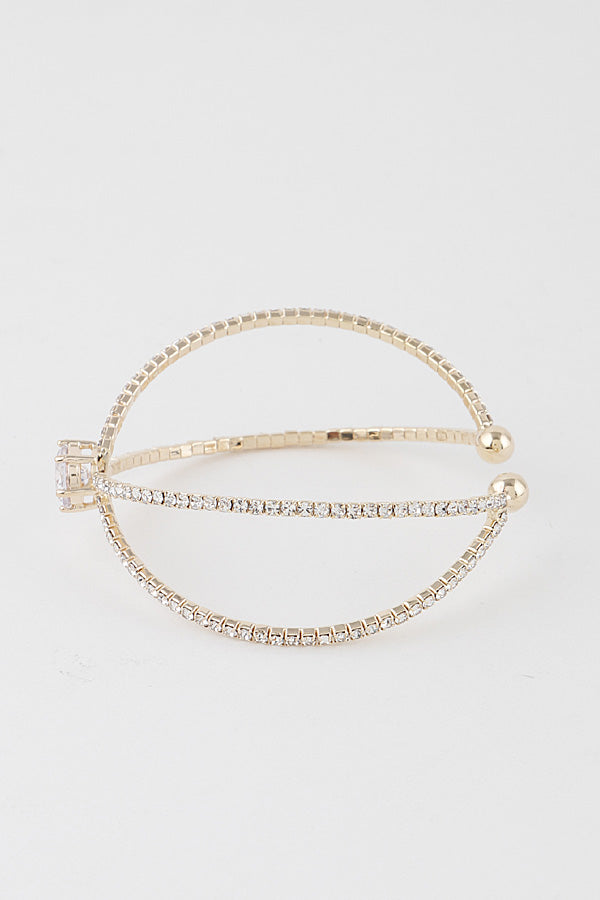 Cubic zirconia crossover cuff bracelet in gold finish shown from side angle against white background