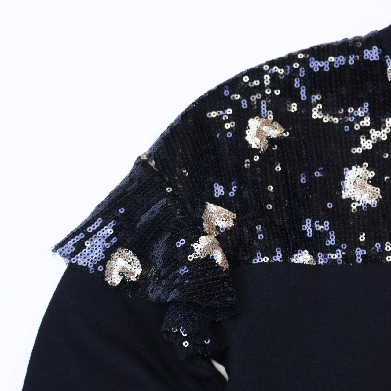 Close-up of black sequin heart sweatshirt showing gold and silver sequin heart embellishments on drop shoulder ruffle