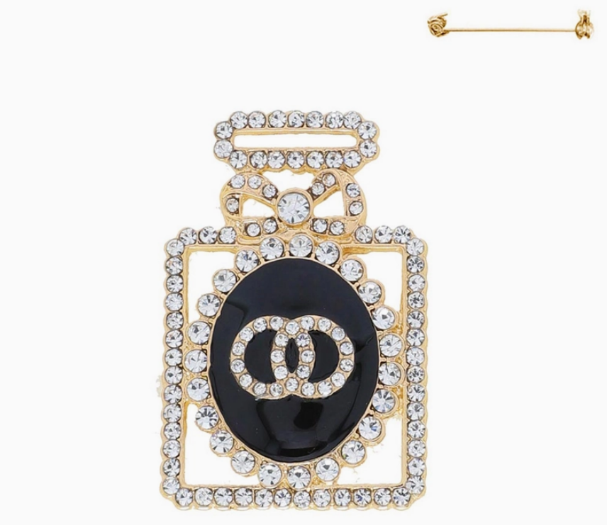 Gold crystal pavé perfume bottle brooch with sparkling rhinestones on white background