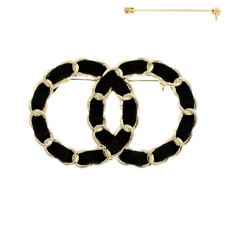 Gold chain-link brooch with black faux leather and interlocking double-circle design, shown with pin back