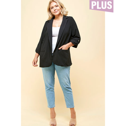 Plus-size woman wearing a black open-front blazer with 3/4 sleeves and front pockets, styled with jeans and a white tank.