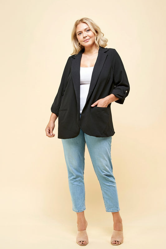 Plus size black open-front blazer full length front view – ruched 3/4 sleeves with silver button tab and patch pockets styled with jeans