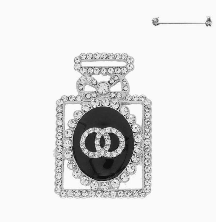Silver crystal pavé perfume bottle brooch with sparkling rhinestones on white background