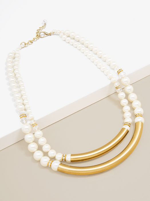 White pearl and gold tube statement necklace with rhinestone accents on neutral background