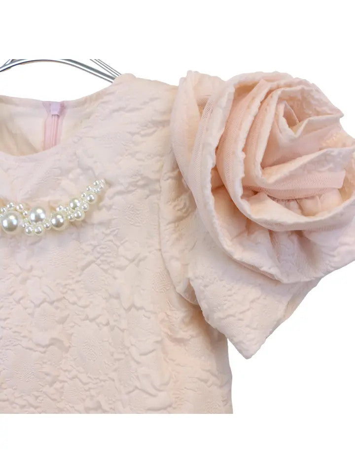 Close-up of blush pink floral brocade dress showing pearl and crystal collar detail and fabric rosette sleeve