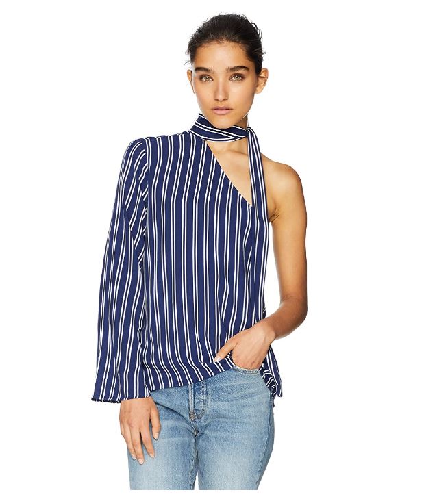 A woman wearing a blue and white striped one-shoulder top with a choker neckline, paired with blue jeans.