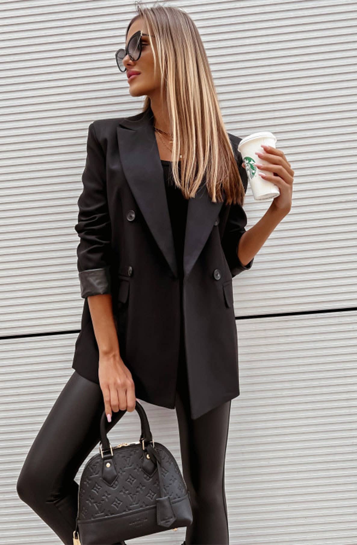 Woman wearing black oversized blazer with black pants and sunglasses holding coffee - chic professional street style outfit