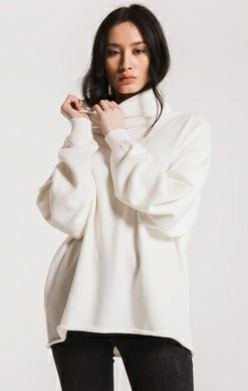 woman wearing a cream turtle neck drop shoulder sweater