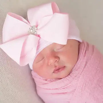 Infant in soft pink hospital beanie with rhinestone ribbon bow wrapped in blanket