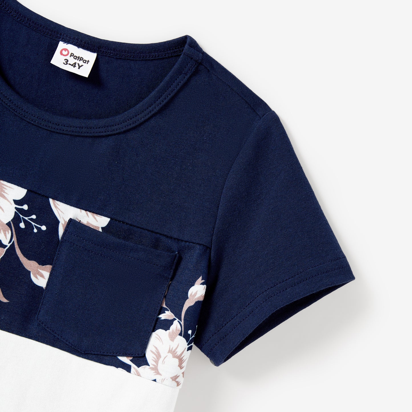 Close-up detail of boys' navy tee showing floral print panel with blush and white flowers and chest pocket