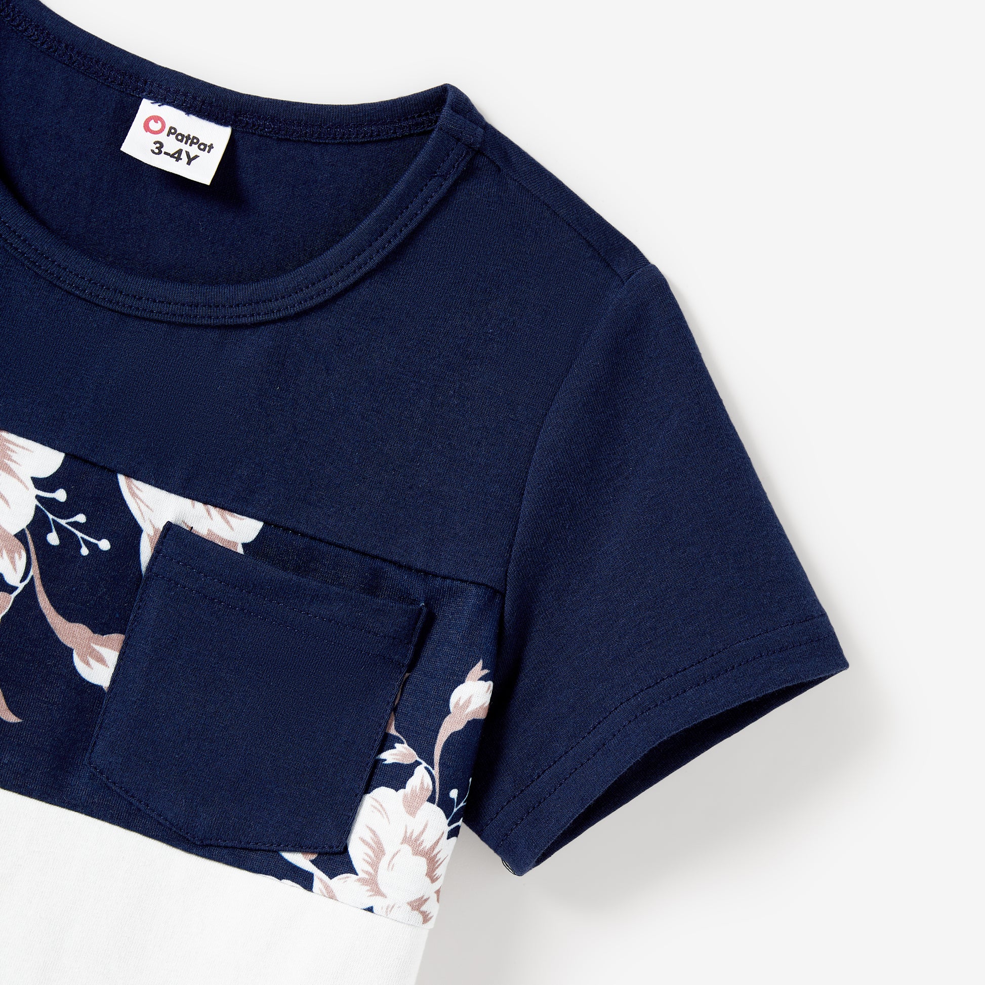 Close-up detail of boys' navy tee showing floral print panel with blush and white flowers and chest pocket
