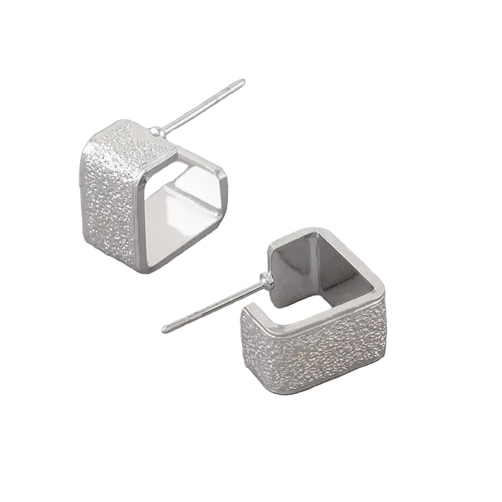 Professional product photo of silver textured square open huggie earrings on pure white background showing 0.5-inch geometric design with textured finish