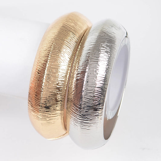 Gold and silver brushed metal textured bangle bracelets stacked together on white background