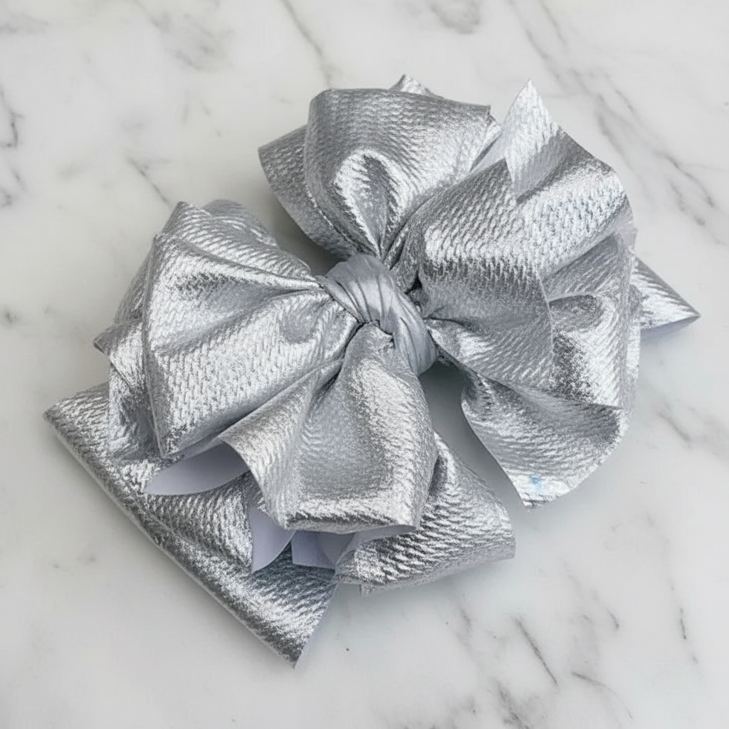 Close-up of shimmering silver metallic bow headband with textured fabric detail
