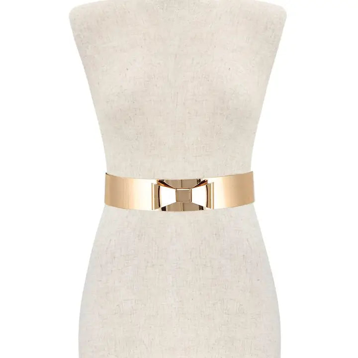 Metal ribbon bow belt styled on dress form showing waist-cinching fit and polished gold bow detail