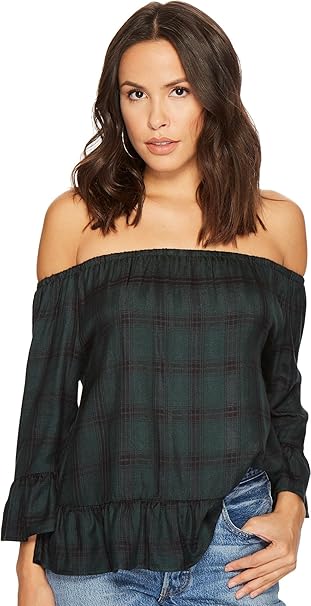 Woman wearing a green plaid off-shoulder top with blue jeans on a white background