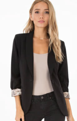 Woman wearing black tailored blazer with snake print lining detail, showing sophisticated structured fit and edgy interior design