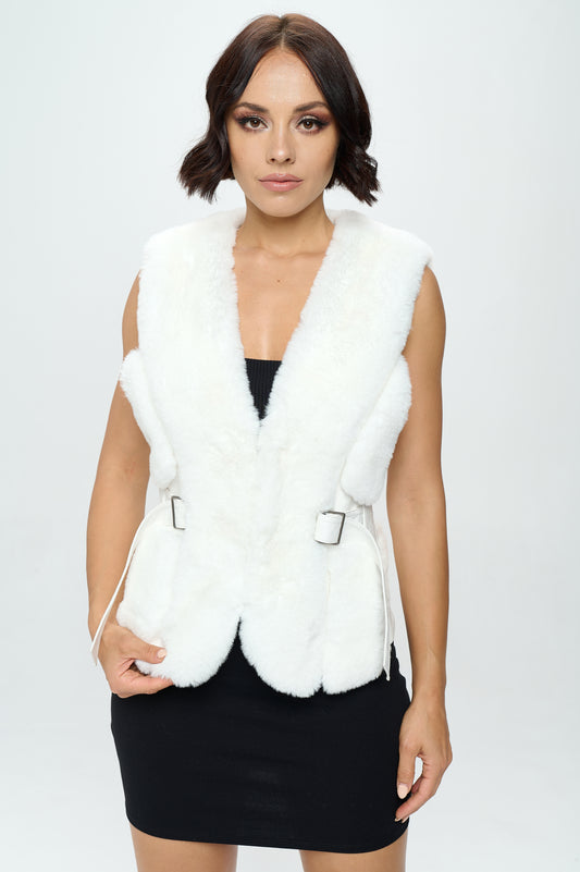 Woman wearing a white fur vest over a black dress on a white background