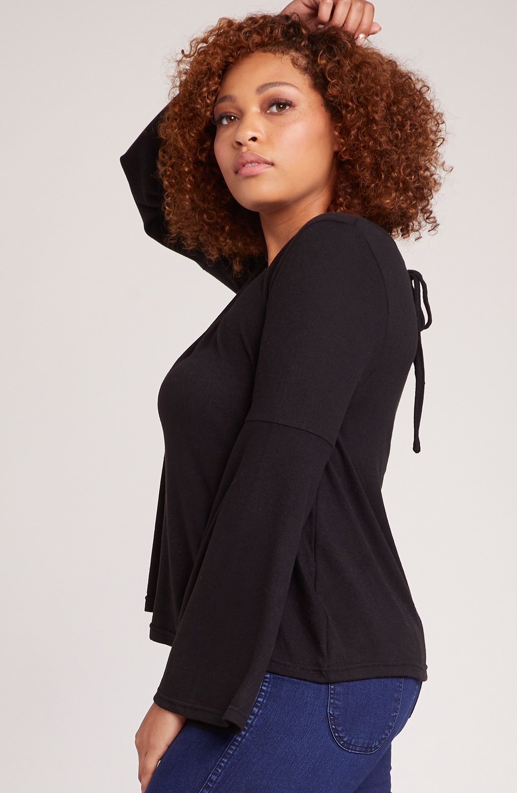 Model wearing black bell sleeve top with keyhole back detail - side angle showing flared sleeves