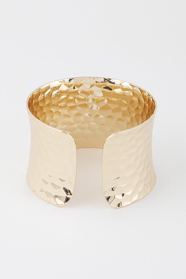 Wide hammered gold cuff bracelet showing adjustable open back and textured surface detail